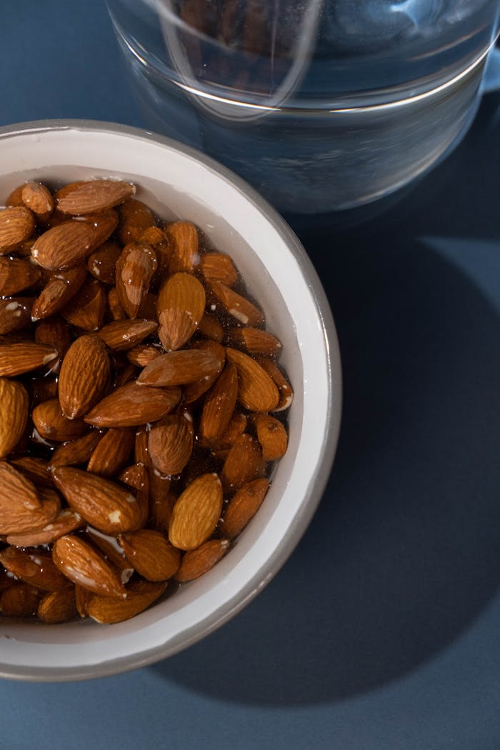 Close-up of soaked almonds in a bowl against a dark blue background, highlighting health and nutrition.
